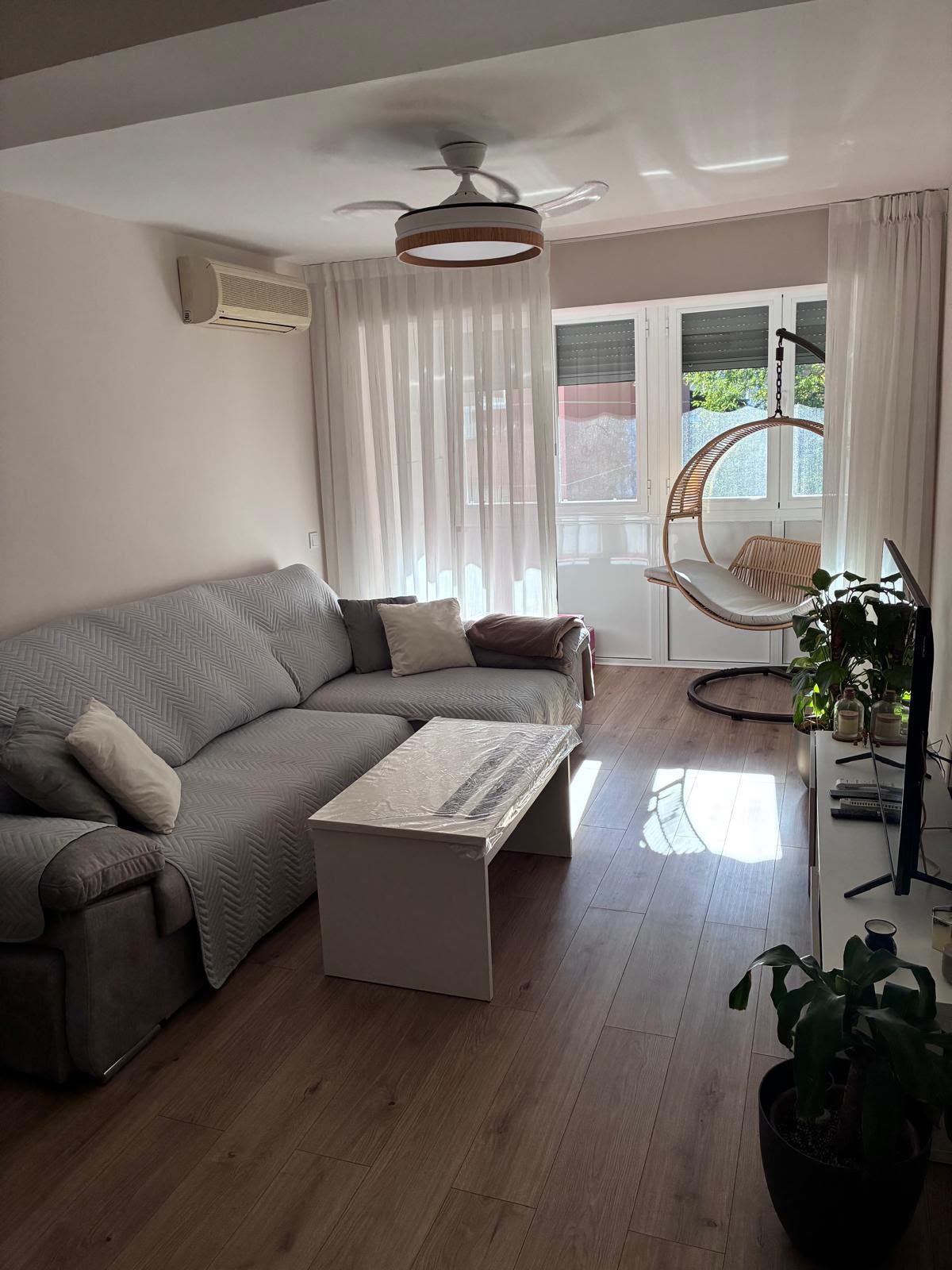 Salón reformado con suelo laminado, paredes claras y salida a la terraza