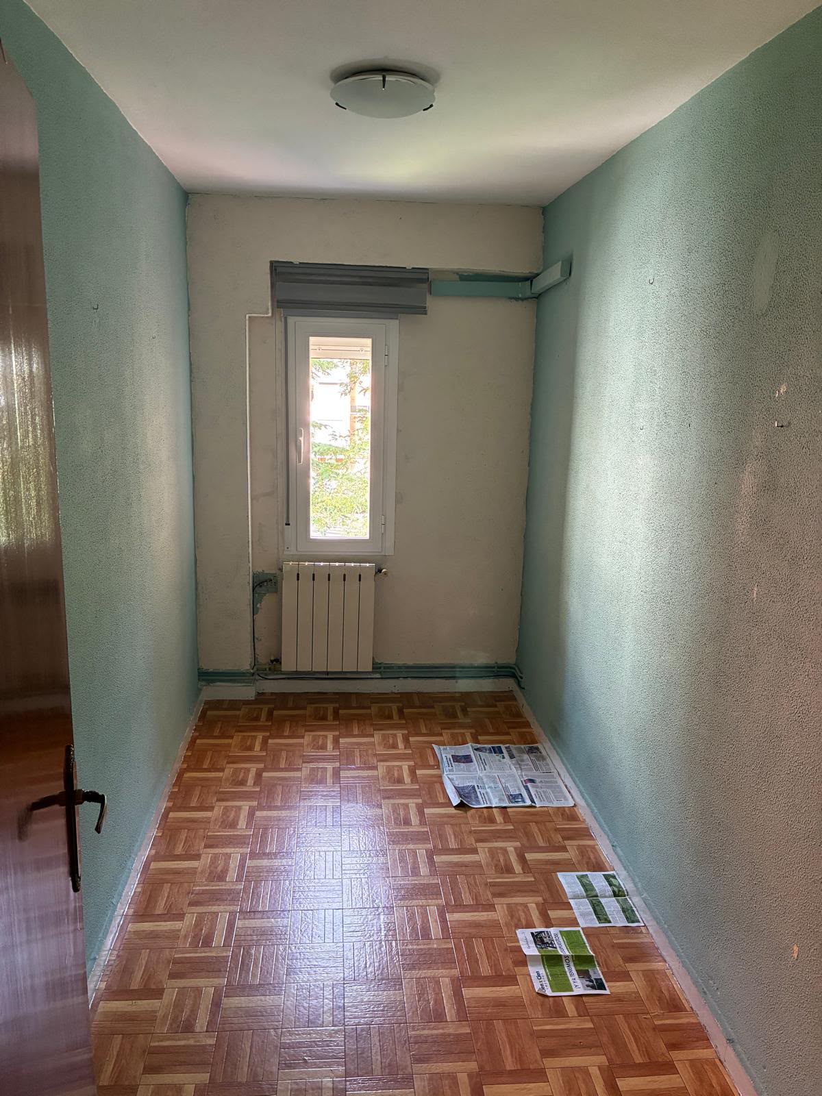 Habitación antes de la reforma, con paredes verdes y suelo antiguo